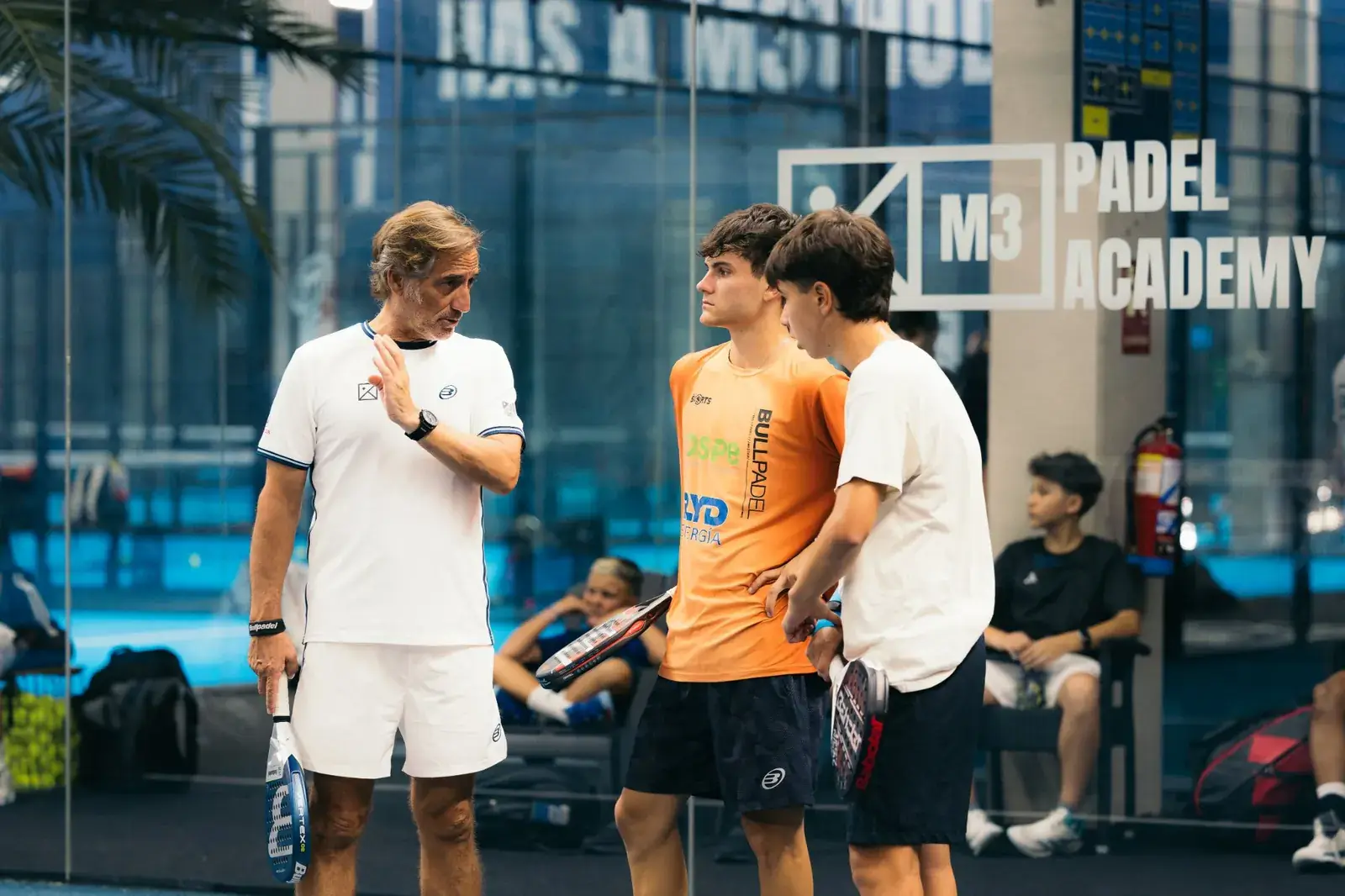 M3 coach with a group of young players on court at the competition academy